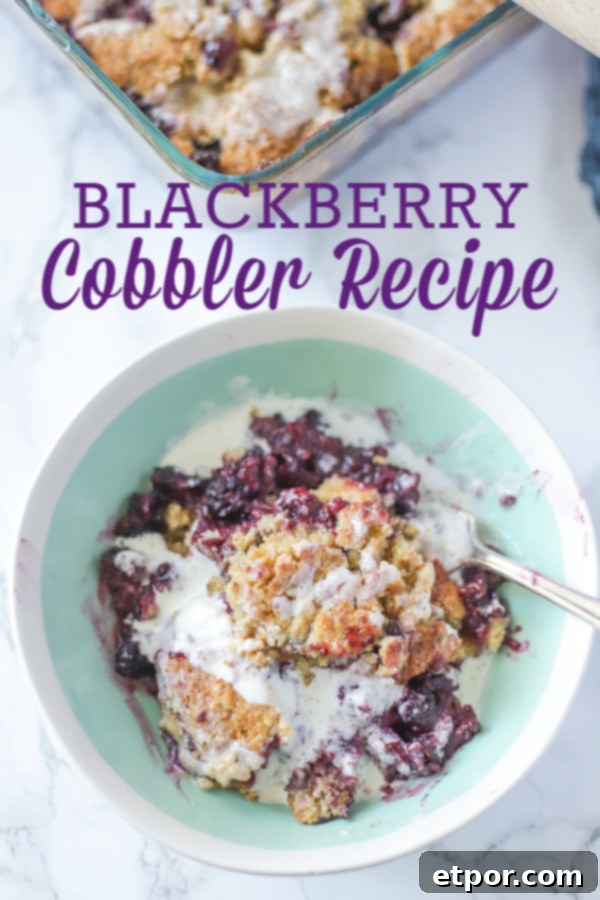 Delicious blackberry cobbler topped with cream in a teal and cream bowl, ready to be served as a delightful dessert.