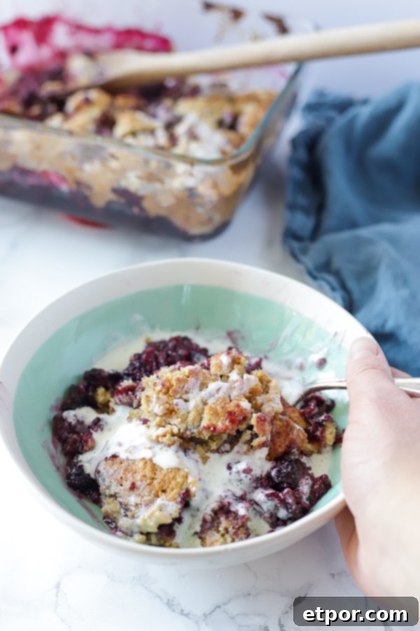 A close-up shot of baked blackberry cobbler in a dish, highlighting the bubbly fruit filling and golden brown topping.