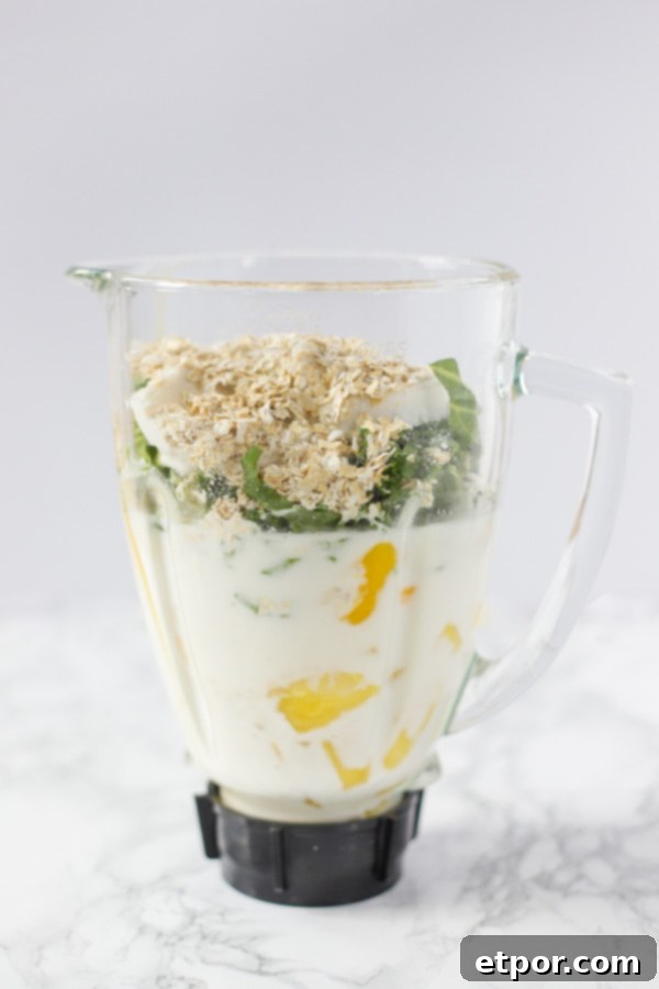 All tropical oatmeal smoothie ingredients are loaded into a blender, ready to be processed into a creamy drink.