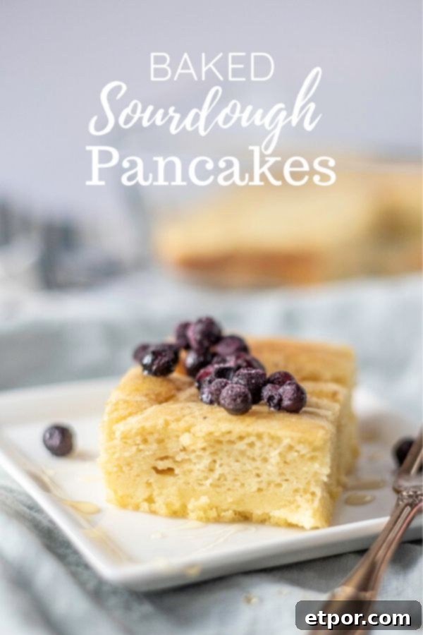 baked sourdough pancake topped with honey and blueberries on a white plate on top blue napkin