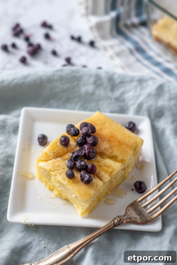 baked sourdough pancake topped with frozen blueberries on a white place with an antique fork