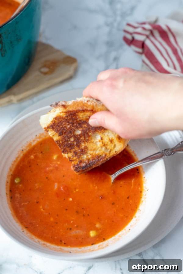 sourdough grilled cheese being dunked into homemade tomato soup