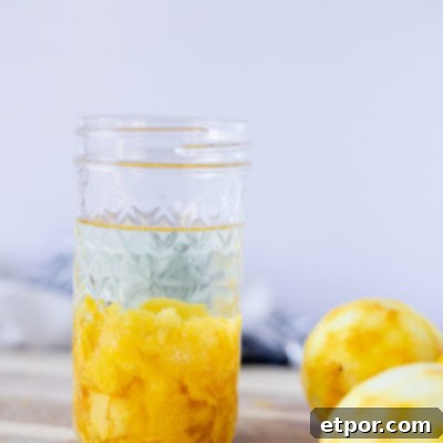 homemade lemon extract in a mason jar on top a wood cutting board with lemons around