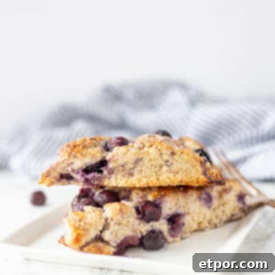 Two freshly baked sourdough scones on a white plate with a blue and white striped towel in the background.