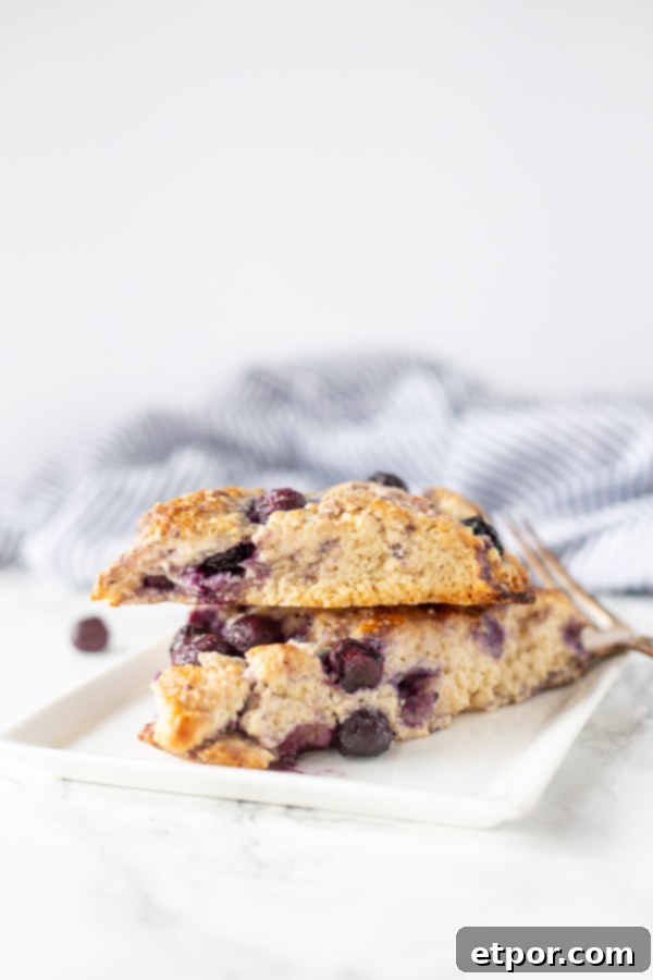 Two freshly baked sourdough scones on a white plate, with a blue and white striped towel in the background.