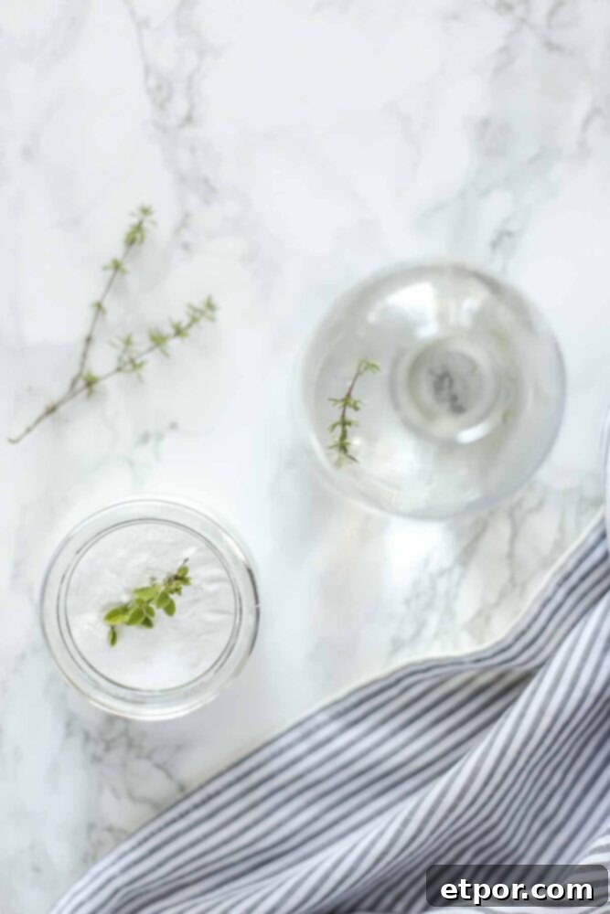 overhead photo of two glasses with cleaning ingredients on a marble countertop with a blue an white stripped towel to the left