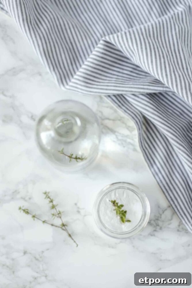 overhead photo of two glass containers of toilet cleaner on a marble countertop with a blue and whit stripped towel in the back corner