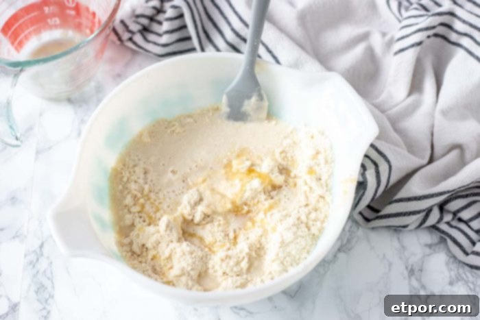 sourdough starter, butter, flour, and honey in a bowl to make sourdough biscuits. Striped black and white towel to the right