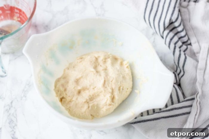 sourdough biscuit dough in a ball in a white bowl with a stripped towel to the right