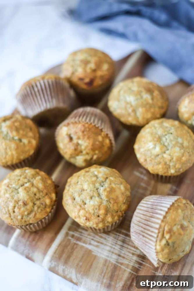 Close-up of a single sourdough banana muffin, showcasing its moist interior and golden crust, with more muffins in the background.