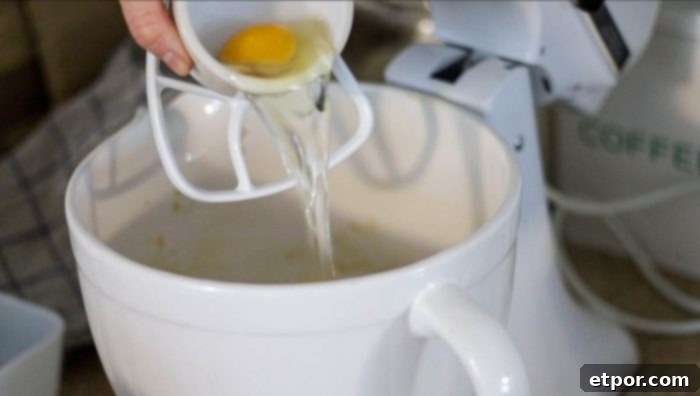 Adding eggs to the sourdough banana muffin batter in a stand mixer.