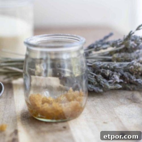Whip Up Your Own Lip Scrub 12 jar of lip sugar scrub on a wood countertop with a bundle of lavender and a glass of sugar in the background