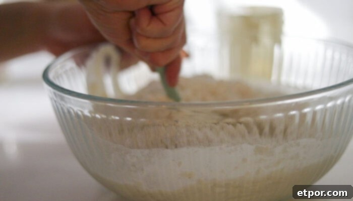 Mixing ingredients together in a glass bowl to form a shaggy dough.