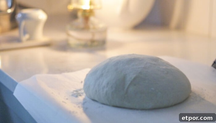 Sourdough bread boule resting on parchment paper.
