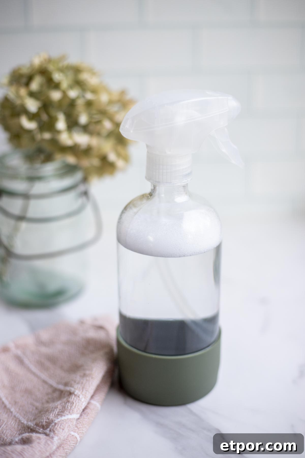 A spray bottle with homemade granite cleaner next to a pink towel.