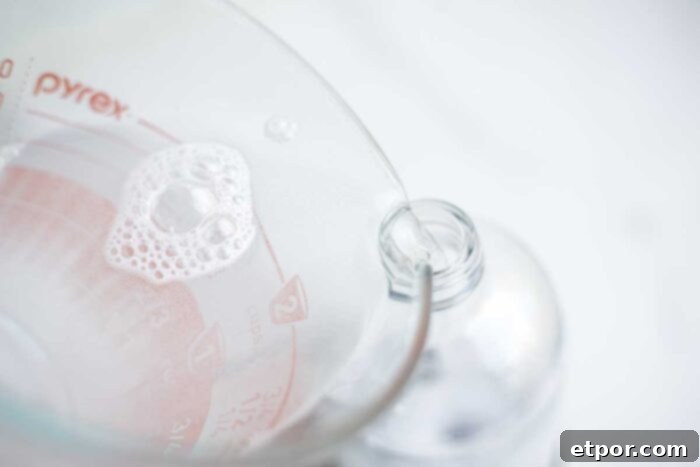 Pouring homemade granite cleaner into a spray bottle.
