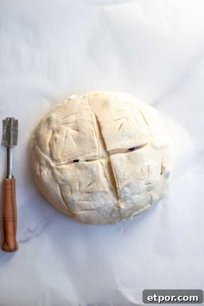 Sourdough bread dough on parchment paper and score with a lame.