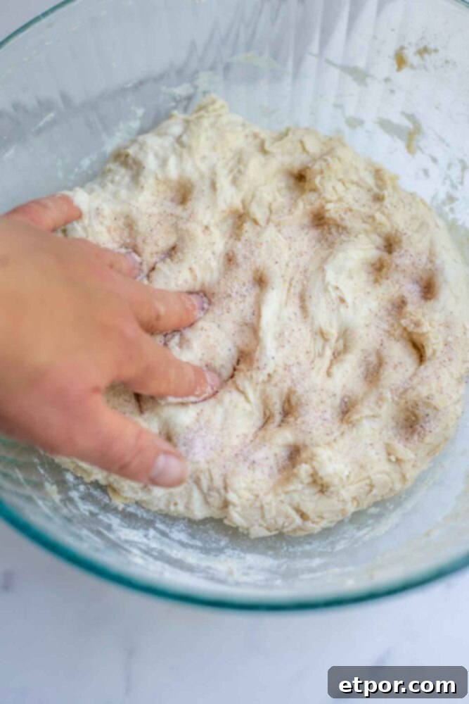 Dimpling in salt to sourdough bread dough in a glass bowl.