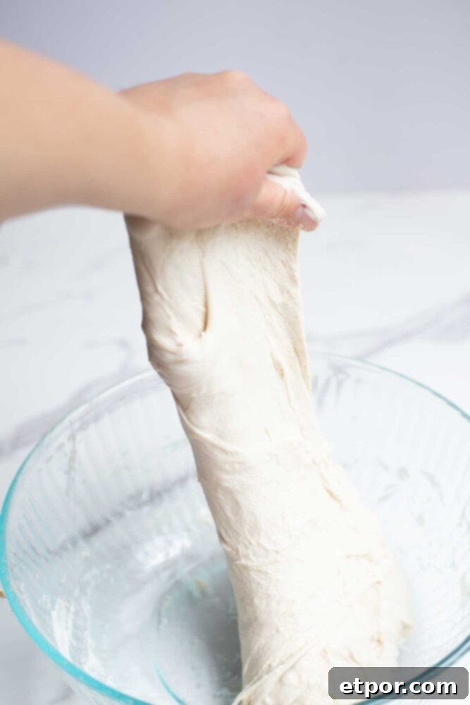 handing pulling up dough for another round of stretch and folds.