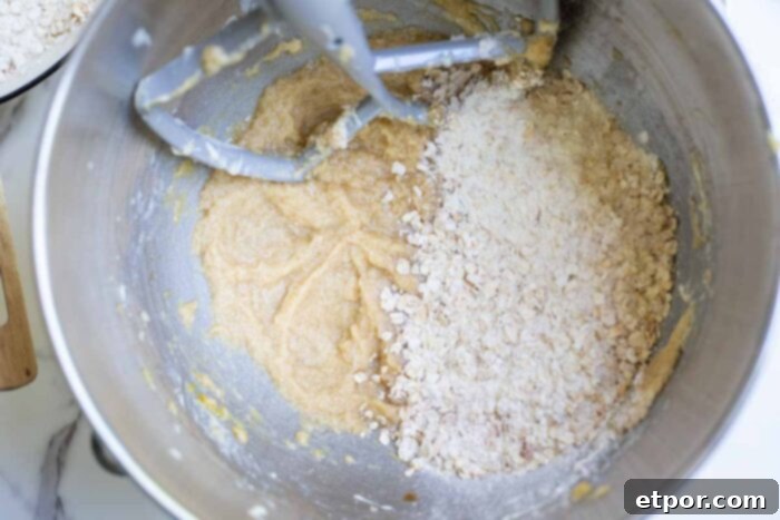 Dry ingredients being slowly added to the wet ingredients in a stand mixer bowl, mixing until just combined.