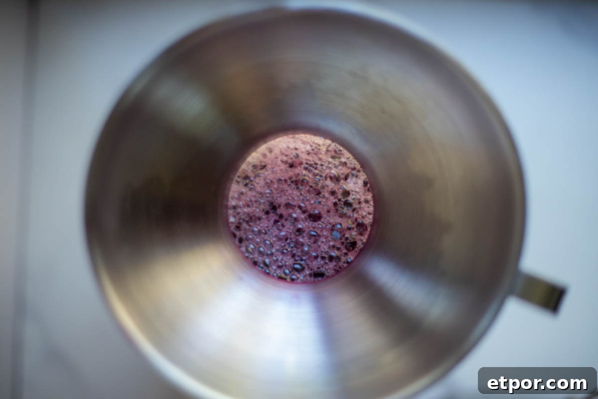 Fresh grape juice poured into a jar with a funnel.