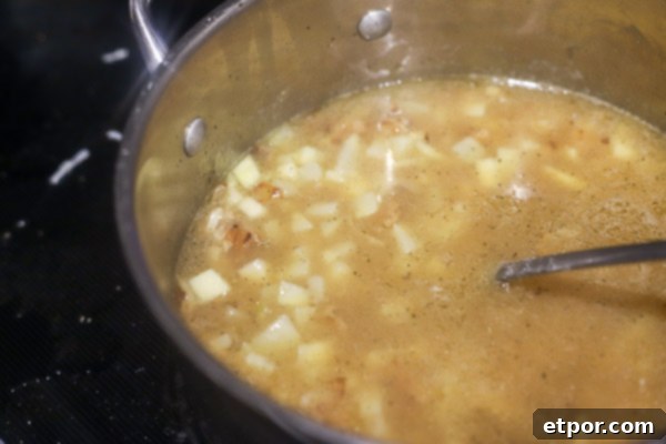 potatoes and broth simmering in a pot for baked potato soup