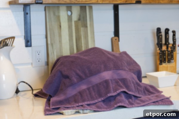 A Crock-Pot covered with thick towels, showing the incubation stage of making homemade yogurt at home.