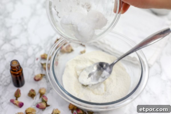 Coconut oil being added to a bowl of DIY deodorant ingredients and stirred with a spoon.