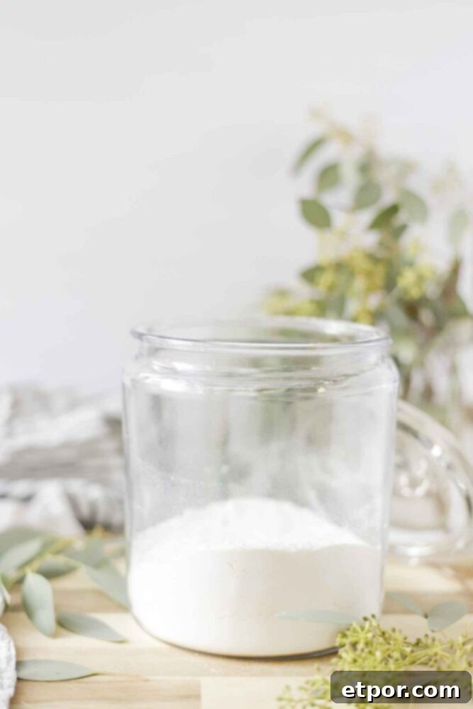 natural and homemade laundry detergent in a glass jar surrounded by eucalyptus 