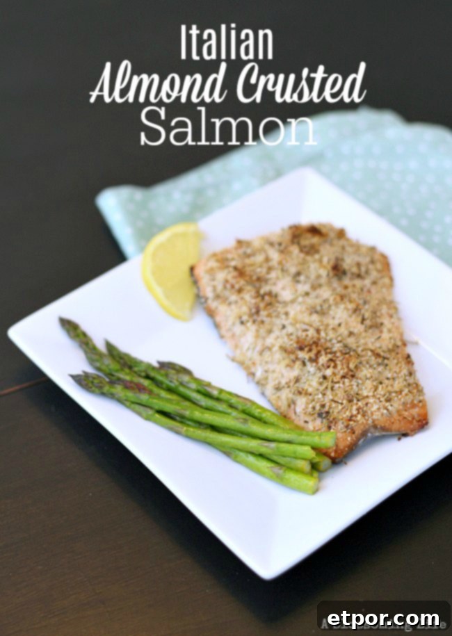 Italian almond crusted salmon on a white plate with asparagus and lemon slice, perfectly cooked and garnished.