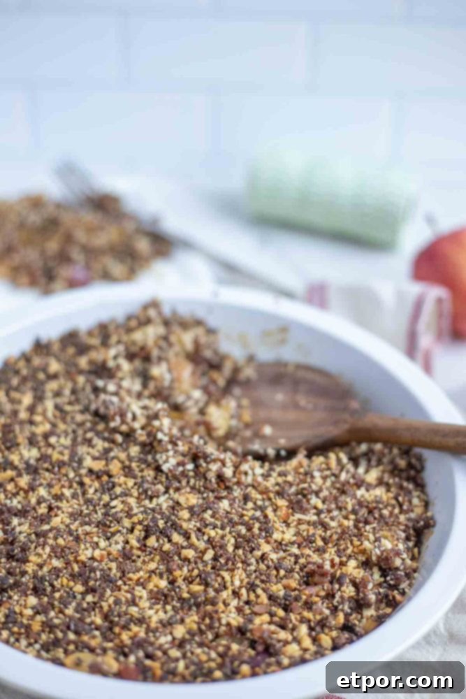 apple crisp in a pie plate with a wooden spoon taking a scoopful out