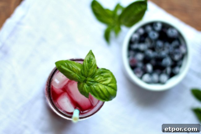 A glass of Blueberry Basil Lemonade on a table, garnished with fresh basil. Focus on the vibrant color and refreshing appeal.