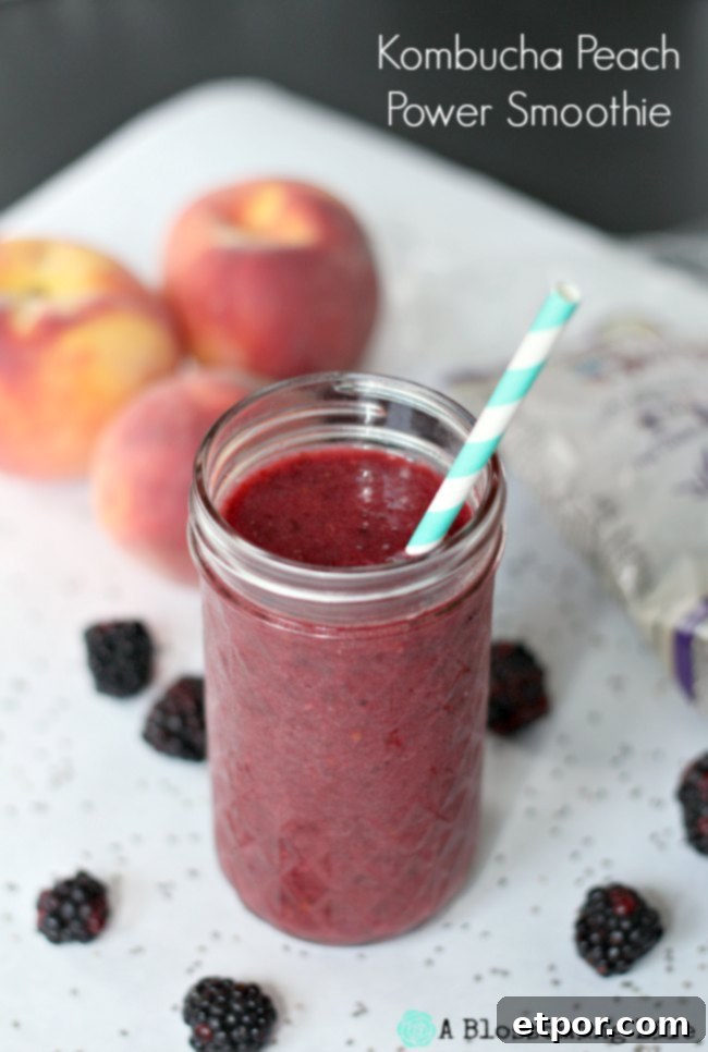 Kombucha berry peach smoothie in a glass mason jar with peaches and blackberries behind it, emphasizing freshness and natural ingredients.
