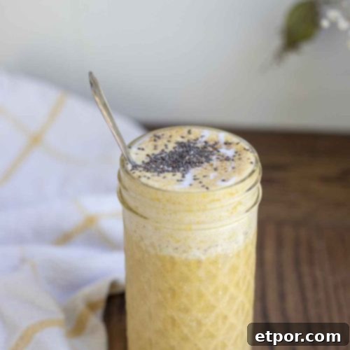 Spiced Pumpkin Pie Bliss Smoothie 11 pumpkin spice smoothie topped with chia seeds in a glass jar with a spoon in the jar. A white and yellow towel is in the background