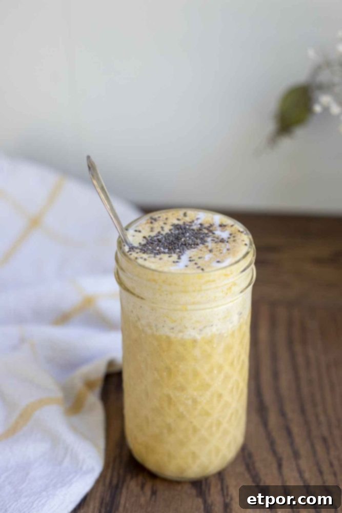 Spiced Pumpkin Pie Bliss Smoothie 6 pumpkin spice smoothie topped with chia seeds in a glass jar with a spoon in the jar. A white and yellow towel is in the background