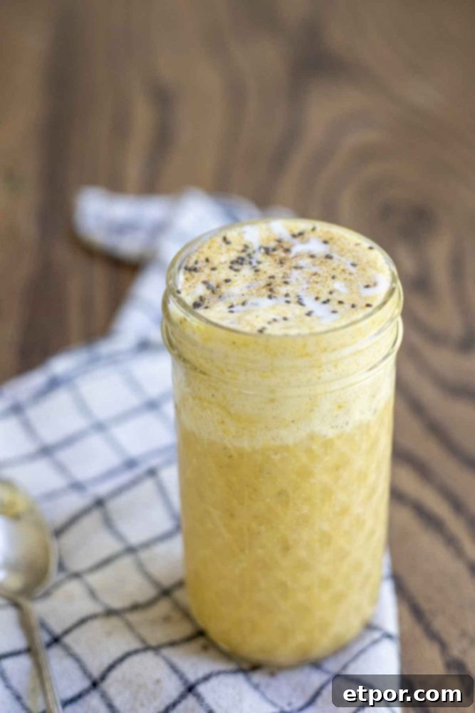 Spiced Pumpkin Pie Bliss Smoothie 10 close up of a pumpkin smoothie topped with chia seeds in a glass jar on a white and black checked towel