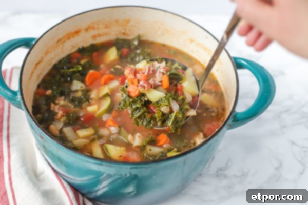 A large Dutch oven filled with hearty classic minestrone soup, with a ladle ready to serve, showcasing its rich texture and ingredients.
