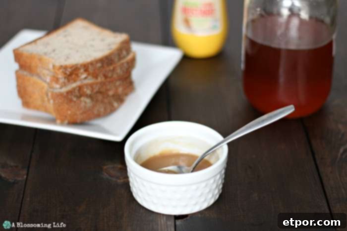 Easy Homemade Honey Mustard 3 homemade honey mustard in a white dish with bread , honey, and mustard in the background