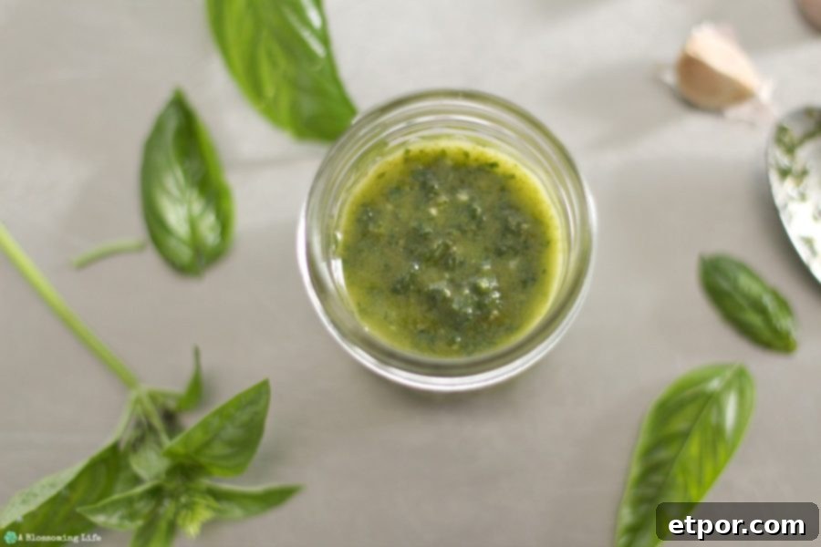 vegan pesto in a glass jar with fresh basil around it