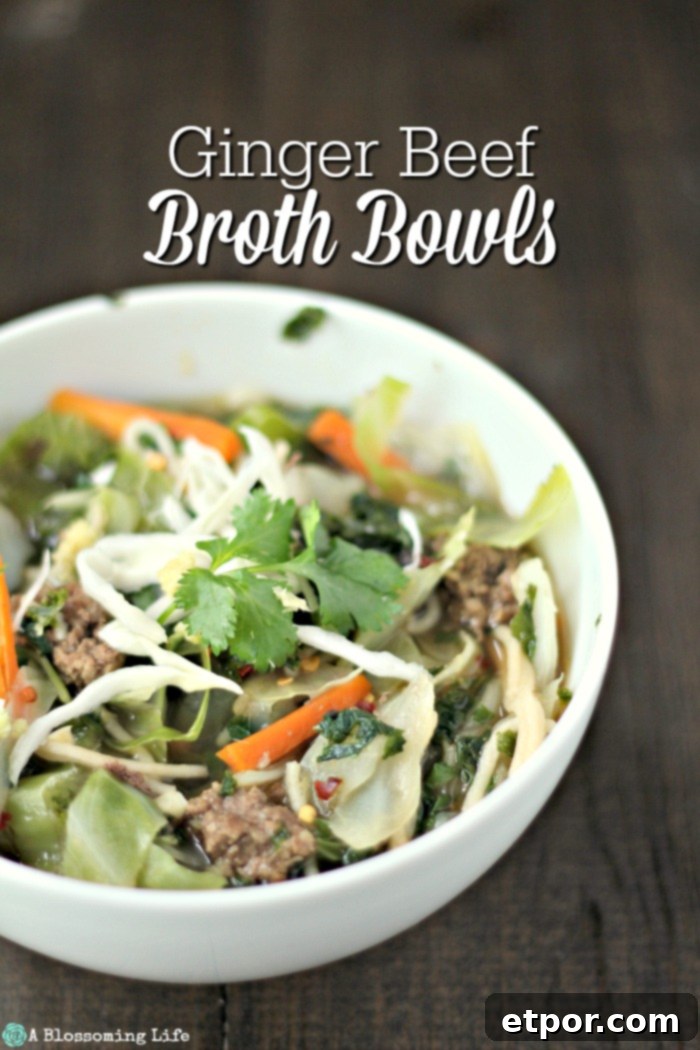 Asian Beef Noodle Soup topped with cilantro in a white bowl on a wood table.