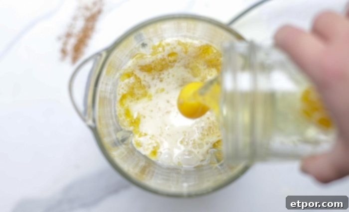 eggs being added to a blender with butter and milk.