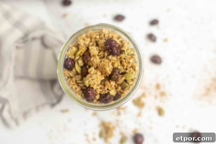Irresistible Pumpkin Spice Granola 4 overhead photo of a jar of pumpkin granola on a marble countertop with the dry ingredients spread around the jar