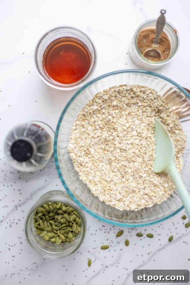 Irresistible Pumpkin Spice Granola 5 a bowl of oats surrounded by jars pf maple syrup, spices, pumpkin seeds, and vanilla