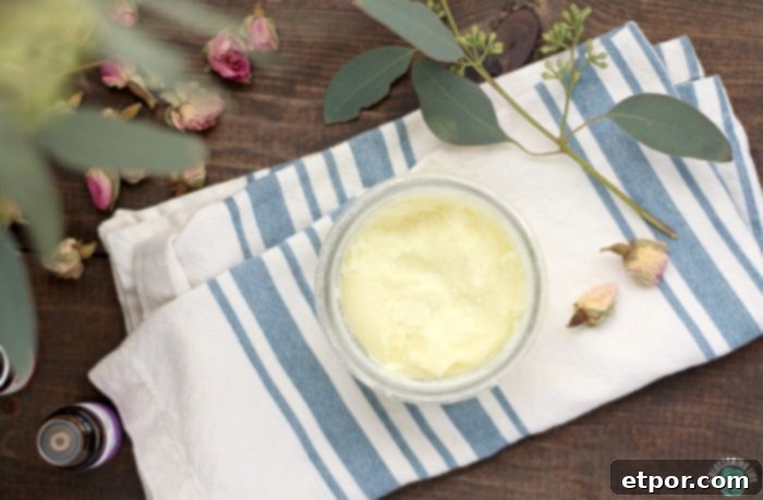 boo boo balm in a glass jar on a stripped cloth napkin. Dried roses and eucalyptus surround the jar