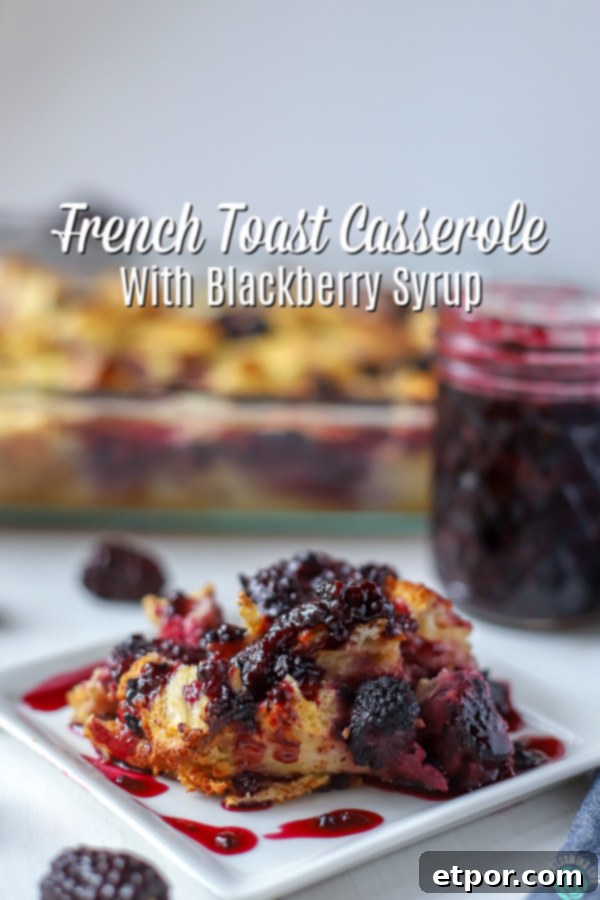 Slice of French Toast Casserole with Blackberries covered with blackberry syrup, with a baking dish and a jar of blackberry syrup in the background