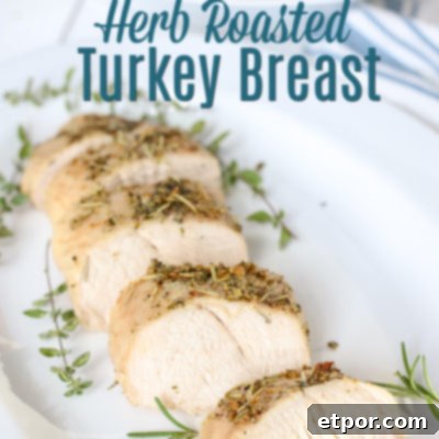 Herb Butter-Infused Roasted Turkey Breast 2 herb roasted turkey breast on a white plate with herbs around it.