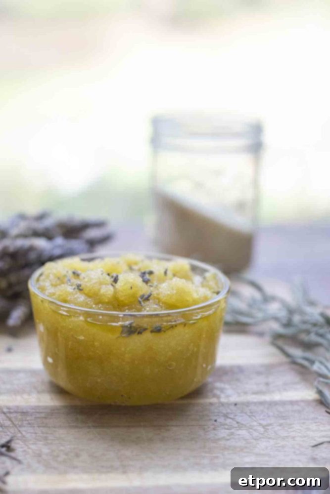 Homemade Lavender Bliss Body Polish 4 jar of lavender body scrub on a wood cutting board. A bundle of dried lavender and a jar of sugar is in the background