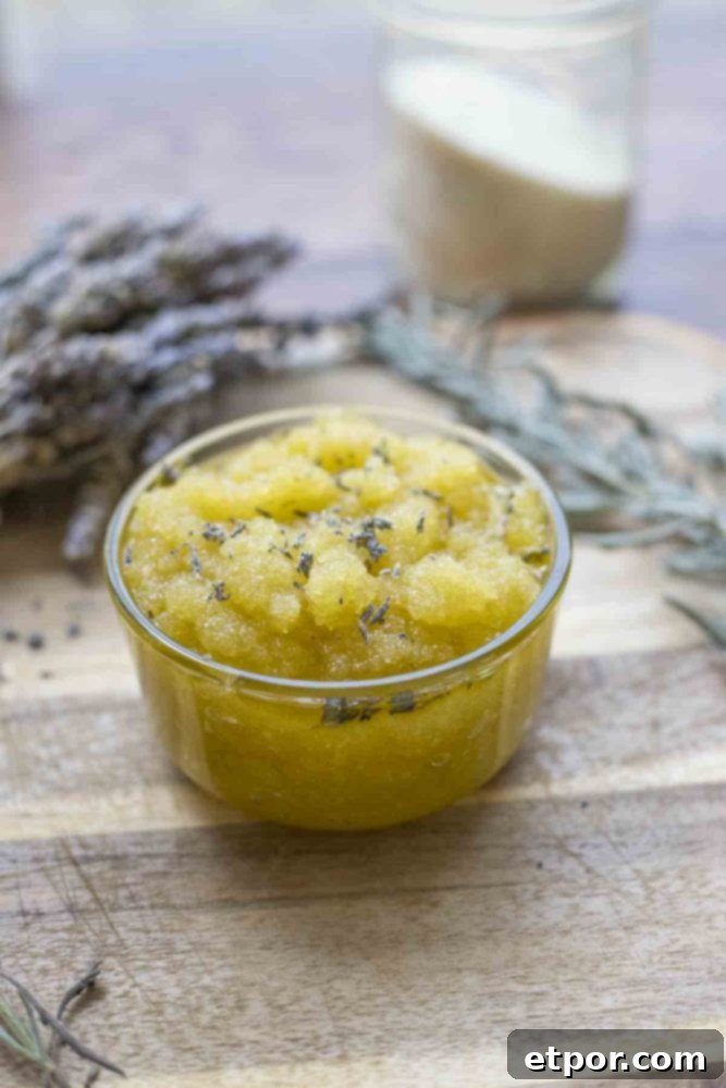 Homemade Lavender Bliss Body Polish 7 jar of lavender sugar scrub topped with dried flowers on a wood cutting board. dried lavender florals and a jar of sugar are in the background