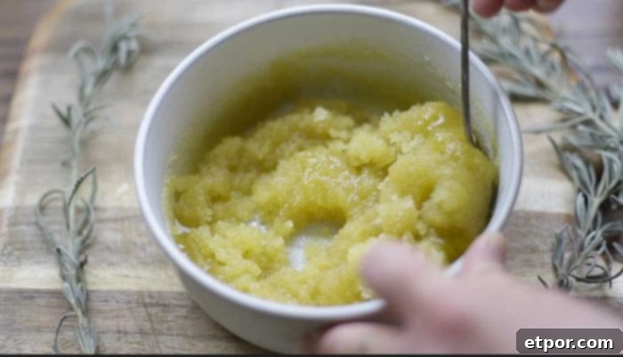 Homemade Lavender Bliss Body Polish 9 mixing together sugar, olive oil, and lavender essential oil in a stone bowl on a wood cutting board with dried lavender