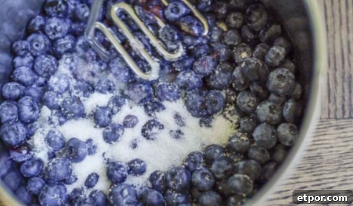 mashing blueberries and sugar in a saucepan